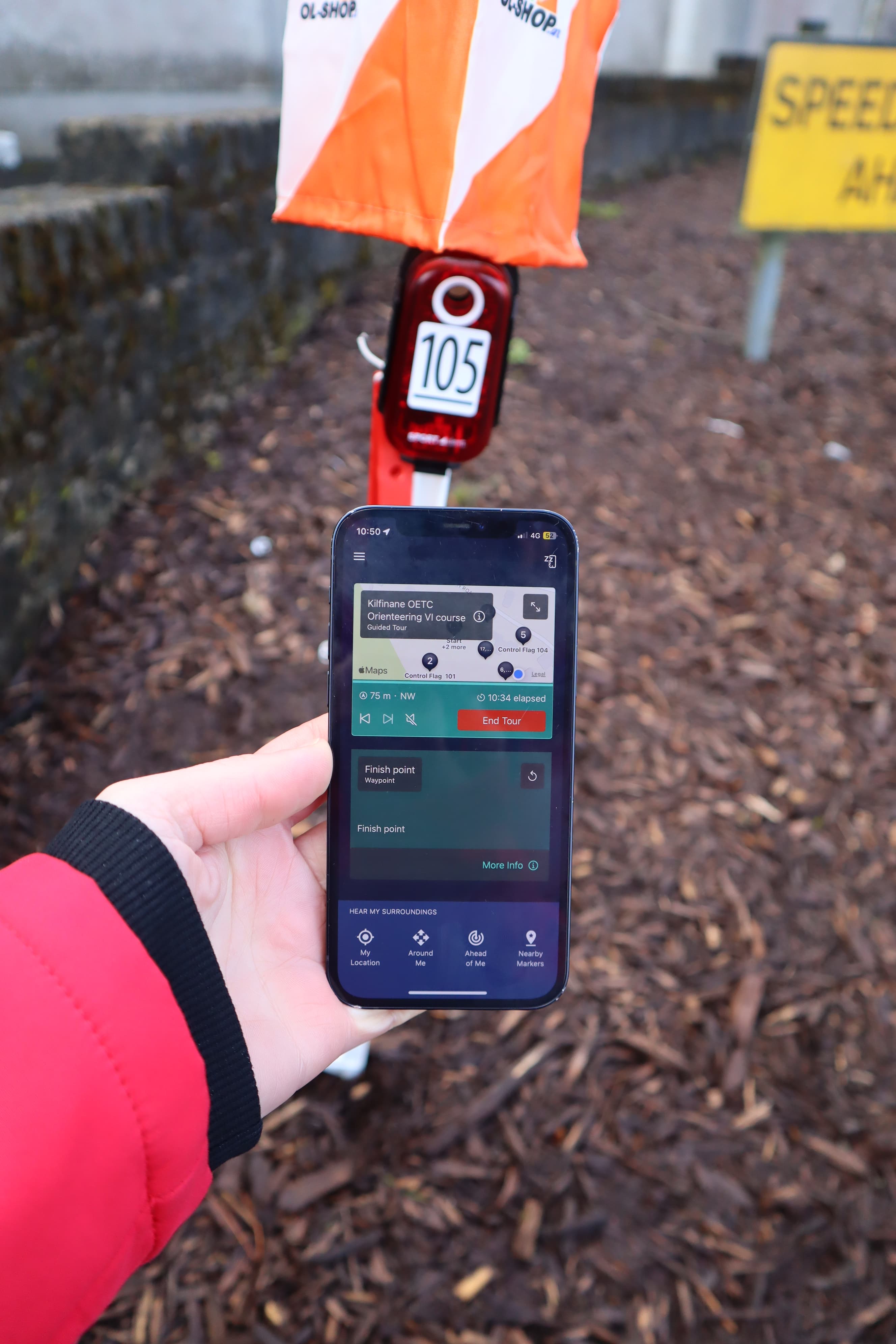 Image of a person holding up their iphone showing the soundscape community app being used to complete an orienteering course