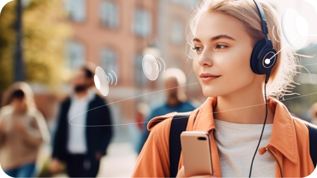 Image of a woman wearing shades and headphones walking down a busy street using Soundscape Community. With supplemental white speakers surrounding her head to show the spatial audio from the application