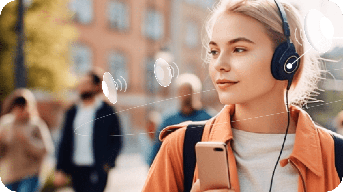 Image of a woman wearing shades and headphones walking down a busy street using Soundscape Community. With supplemental white speakers surrounding her head to show the spatial audio from the application